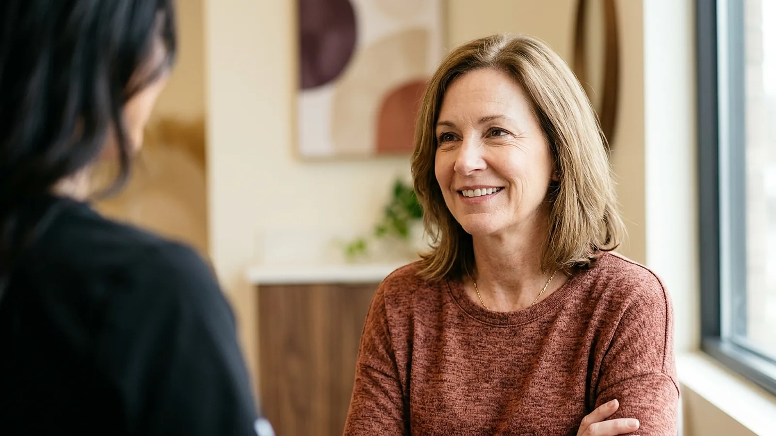A woman in her fifties smiling as she talks with her provider